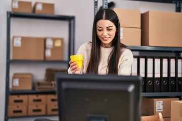Young beautiful hispanic woman ecommerce business worker drinking coffee using computer at office