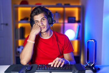 Young hispanic man playing video games thinking looking tired and bored with depression problems with crossed arms.