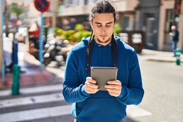 Young man using touchpad with serious expression at street