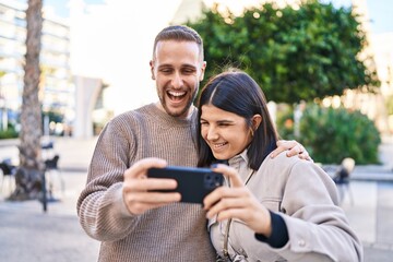 Man and woman couple smiling confident using smartphone at street