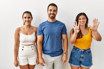 Group of young hispanic people standing over isolated background showing and pointing up with fingers number nine while smiling confident and happy.