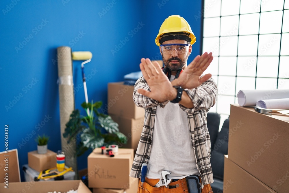 Canvas Prints Young hispanic man with beard working at home renovation rejection expression crossing arms and palms doing negative sign, angry face