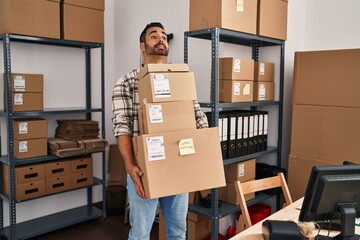 Young hispanic man ecommerce business worker holding packages at office