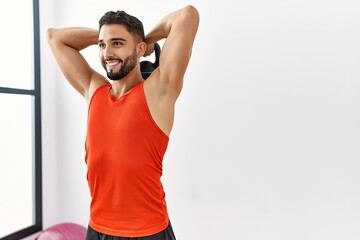 Young arab man smiling confident training with kettlebell at sport center