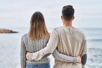 Man and woman couple hugging each other on back view at seaside