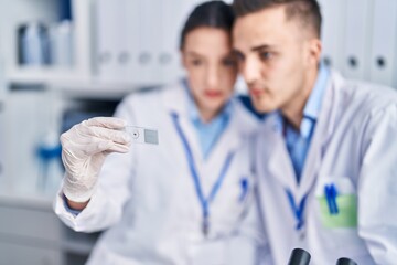 Man and woman scientists looking sample at laboratory