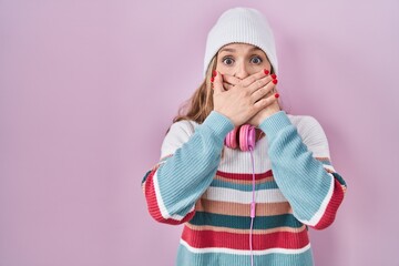 Young blonde woman standing over pink background shocked covering mouth with hands for mistake....