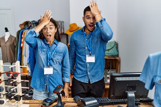 Young interracial people working at retail boutique surprised with hand on head for mistake, remember error. forgot, bad memory concept.