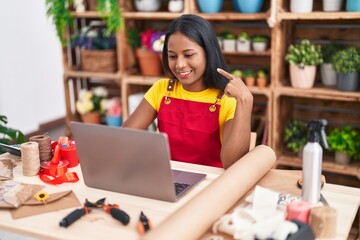 Young indian woman working at florist shop doing video call smiling happy pointing with hand and finger