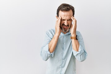 Middle age hispanic man with beard standing over isolated background with hand on head, headache because stress. suffering migraine.