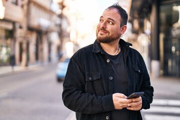 Young hispanic man smiling confident using smartphone at street