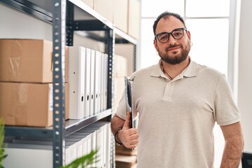 Young hispanic man e-commerce business worker holding clipboard at office