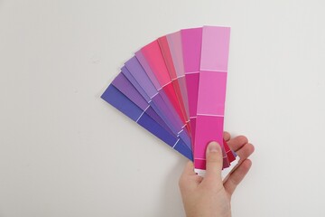 Man with palette choosing color for painting wall indoors, closeup. Interior design