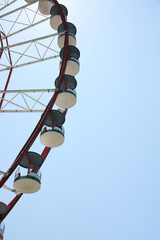 Beautiful large Ferris wheel and palm tree against blue sky, low angle view