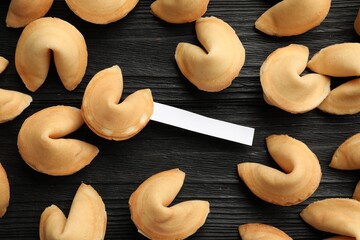 Tasty fortune cookies with predictions on black wooden table, flat lay. Space for text