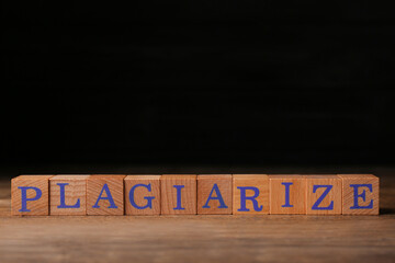 Wooden cubes with word Plagiarize on table, space for text