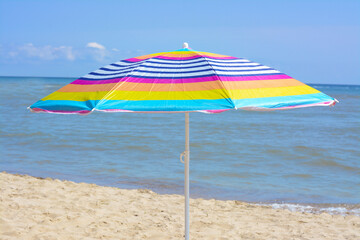 Fototapeta premium Colorful striped umbrella on beach near sea