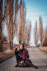 Young woman with a scarf meditating on a rural railroad, finding peace away from the crowded city