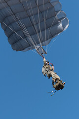 Detalle de un paracaidista militar haciendo un salto de entrenamiento al atardecer