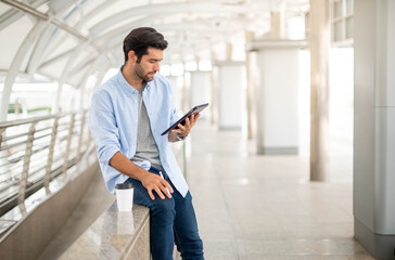 The young man using a tablet to working at out of office. The man wearing casual cloth and feeling...