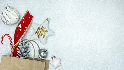 new year presents and christmas ornaments in paper bag on festive silver background