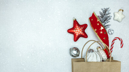 christmas paper bag with gift, toys and decorations on silver background. flat lay, top view.