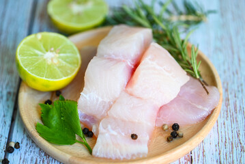 Fish fillet on wooden plate with ingredients celery for cookin, fresh raw pangasius fish fillet with lemon lime, meat dolly fish tilapia striped catfish