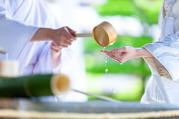 神社の手水舎にてお清めする女性