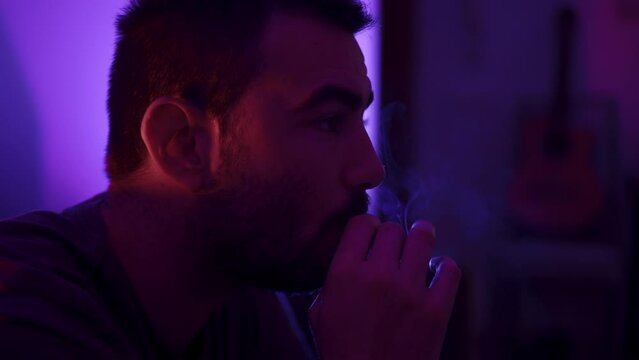 Close-up side profile shot of a man smoking a cigarette
