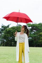 雨の公園で傘をさしている女性