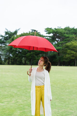 雨の公園で傘をさしている女性