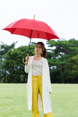 雨の公園で傘をさしている女性