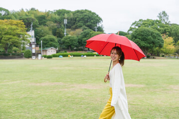 雨の公園で傘をさしている女性
