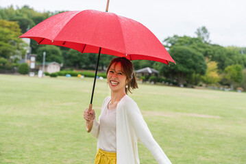 雨の公園で傘をさしている女性