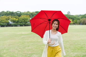 雨の公園で傘をさしている女性