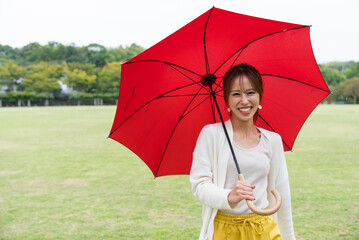 雨の公園で傘をさしている女性