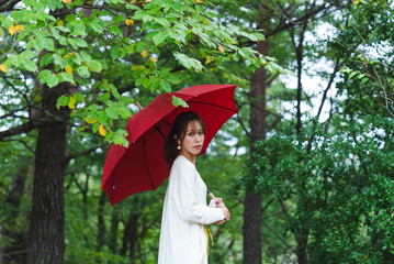 雨の公園で傘を持っている女性