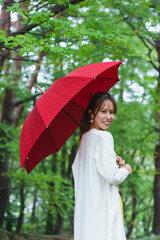 雨の公園で傘を持っている女性