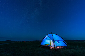 the blue tent is on the grassland. The tent is under the stars