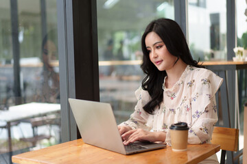 Fototapeta na wymiar Charming asian businesswoman sitting working on laptop in office.