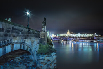 Fototapeta premium Charles bridge and Vltava river at night with blurred boat movement, Prague