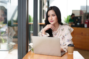 Charming asian businesswoman sitting working on laptop in office.