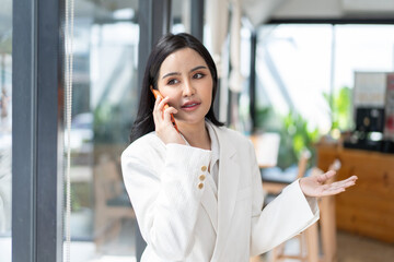 Asian woman with smartphone standing against street blurred building background.