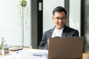 Portrait of young man sitting at his desk in the office, Businessman having coffee and doing his work in cafe.