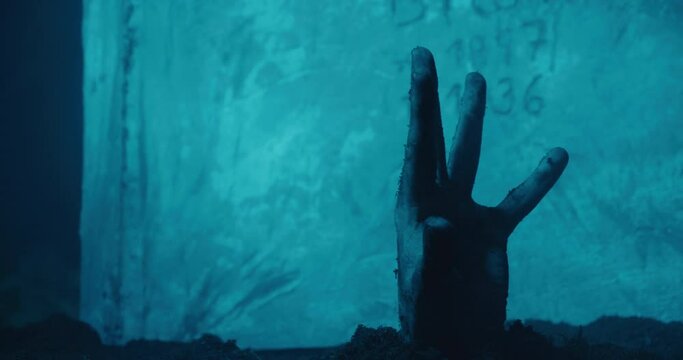 Hand sticking out from grave, tombstone in background, living dead concept, horror moonlight atmosphere