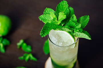 mojito cocktail with lime and mint leaves on a wooden table, refreshing cold drink with rum