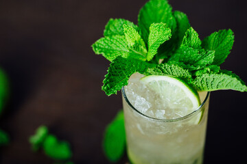 mojito cocktail with lime and mint leaves on a wooden table, refreshing cold drink with rum