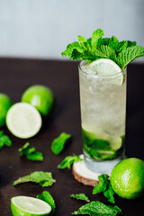 mojito cocktail with lime and mint leaves on a wooden table, refreshing cold drink with rum