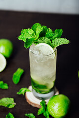 mojito cocktail with lime and mint leaves on a wooden table, refreshing cold drink with rum