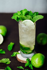 mojito cocktail with lime and mint leaves on a wooden table, refreshing cold drink with rum